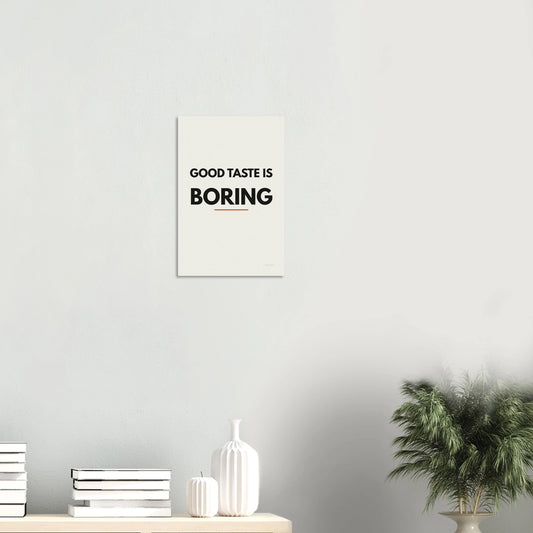 Good Taste Is Boring statement poster in a minimal white room with shelf and plant