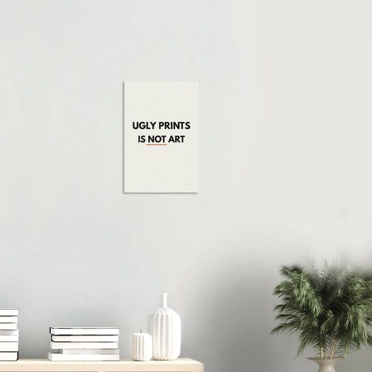 Ugly Prints Is Not Art statement poster in a minimal white room with shelf and plant
