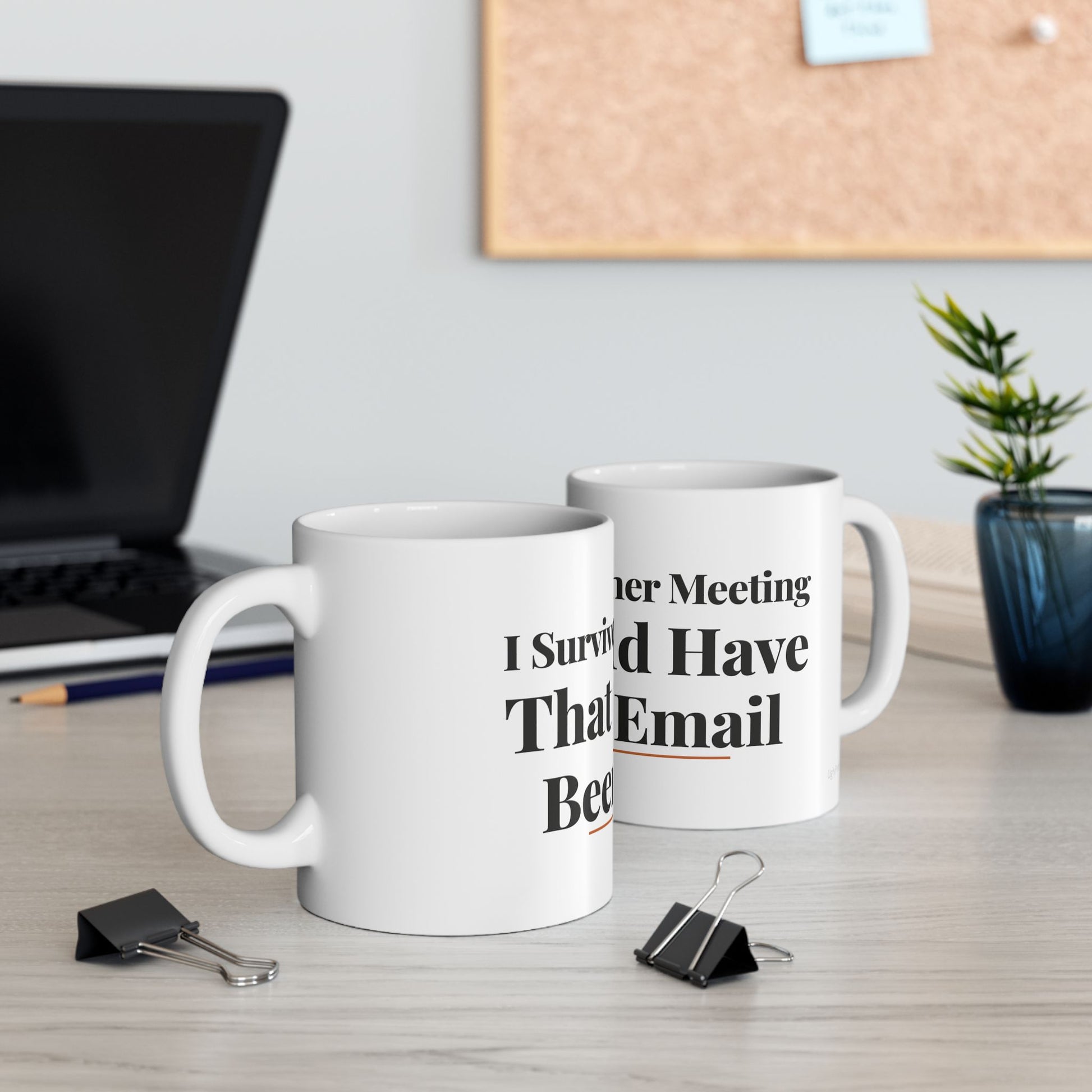 I Survived Another Meeting funny typography mugs on a modern office desk with laptop cork board and plant