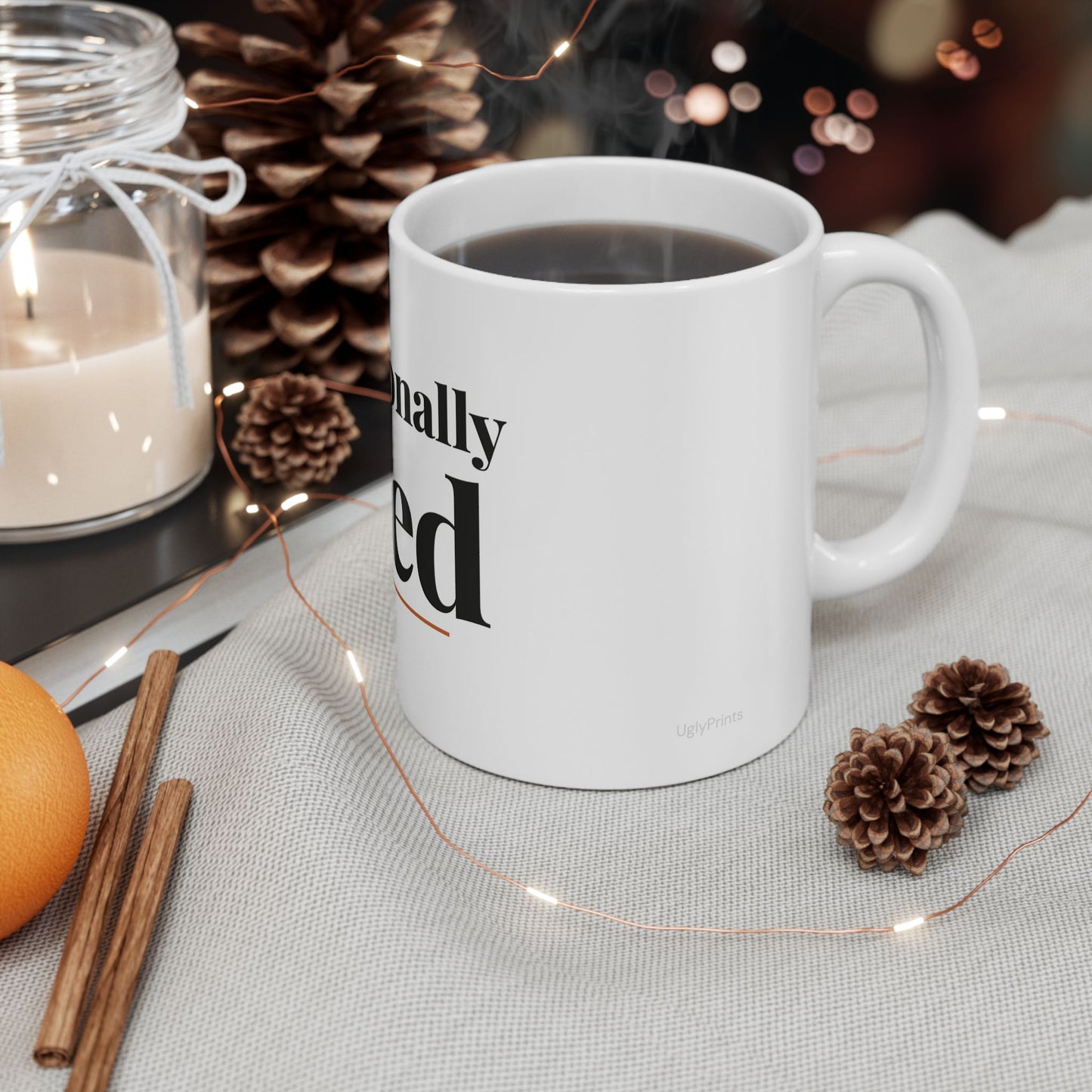 Professionally Tired funny office mug styled in a warm cosy setting with pine cones cinnamon and fairy lights